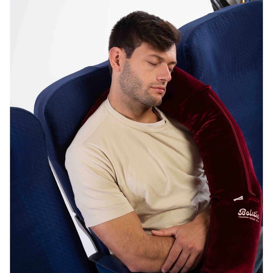 Business traveler resting upright with Bolstie travel pillow in economy class seat